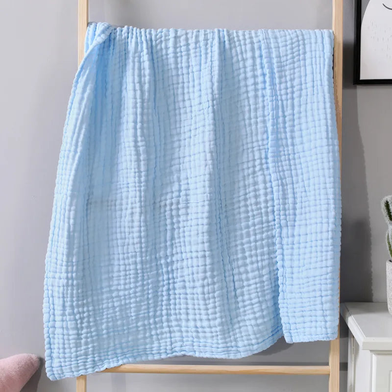 Light blue soft muslin cotton blanket draped over a wooden rack.