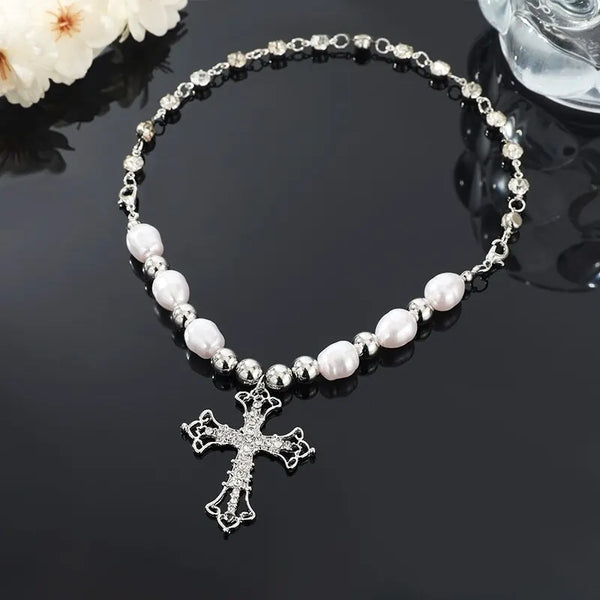 Collier argenté avec de petites perles et un pendentif croix sur fond noir.