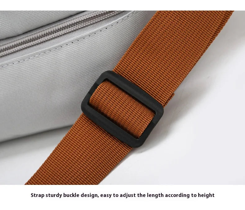 A close-up of a brown strap with a black buckle, used to adjust the length on a gray travel duffle bag.