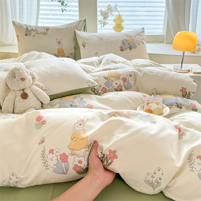 A set of cute dog print duvet covers and pillowcases in cream and pastel colors displayed on a bed.