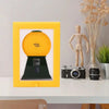 A yellow frame displays a vintage rotating candy display with a dust cover and a wooden figure.