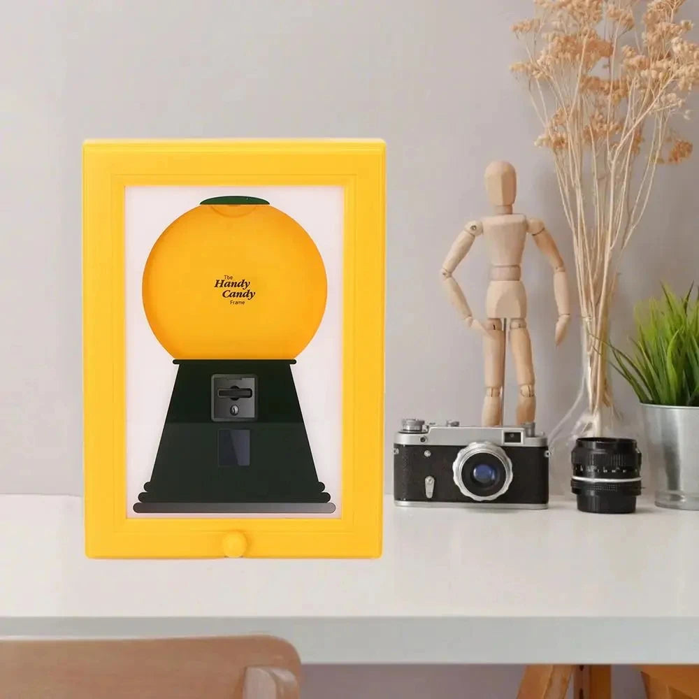 A yellow frame displays a vintage rotating candy display with a dust cover and a wooden figure.