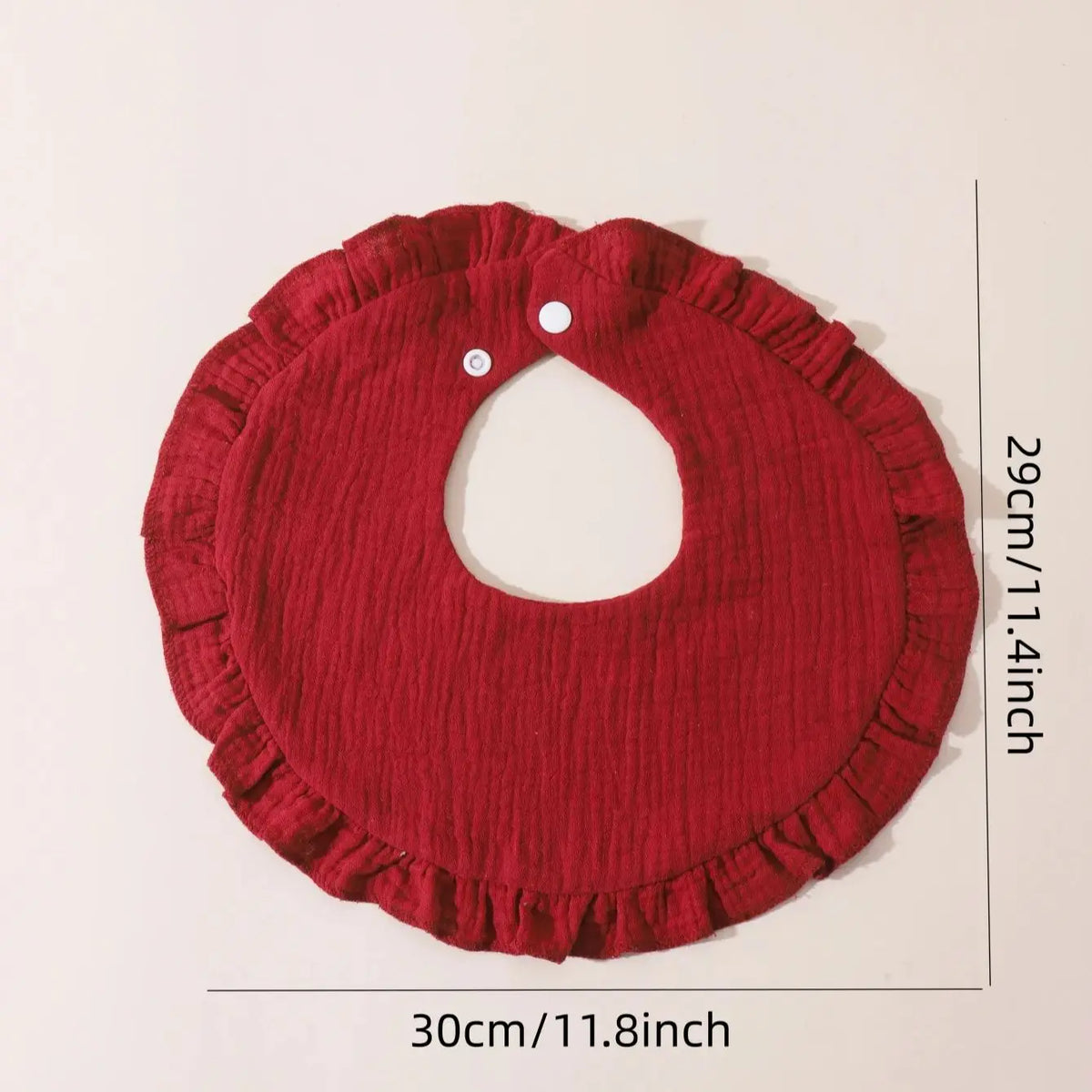 A red soft cotton baby bib with a ruffle trim shown flat.