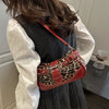 A close-up of a red leopard print PU leather shoulder bag worn by a person, set against a dark background.