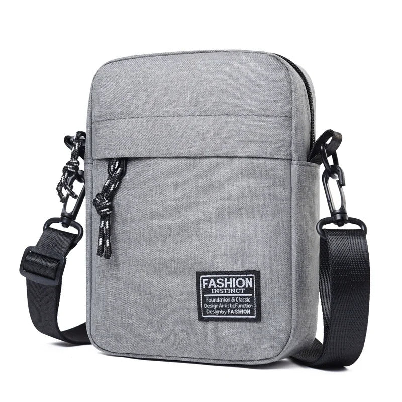 A gray mini crossbody phone bag with a black adjustable strap is shown against a white background.