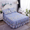 Jupe de lit à motifs floraux bleu clair avec ourlet froncé, présentée sur un lit dans une chambre.