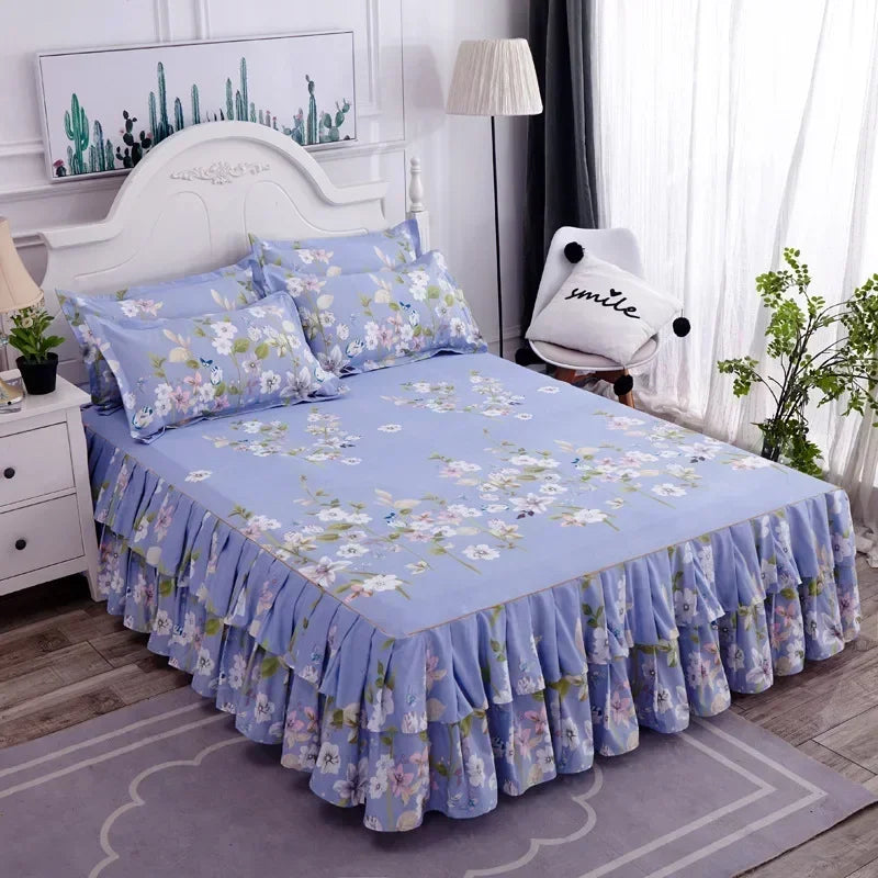 Jupe de lit à motifs floraux bleu clair avec ourlet froncé, présentée sur un lit dans une chambre.