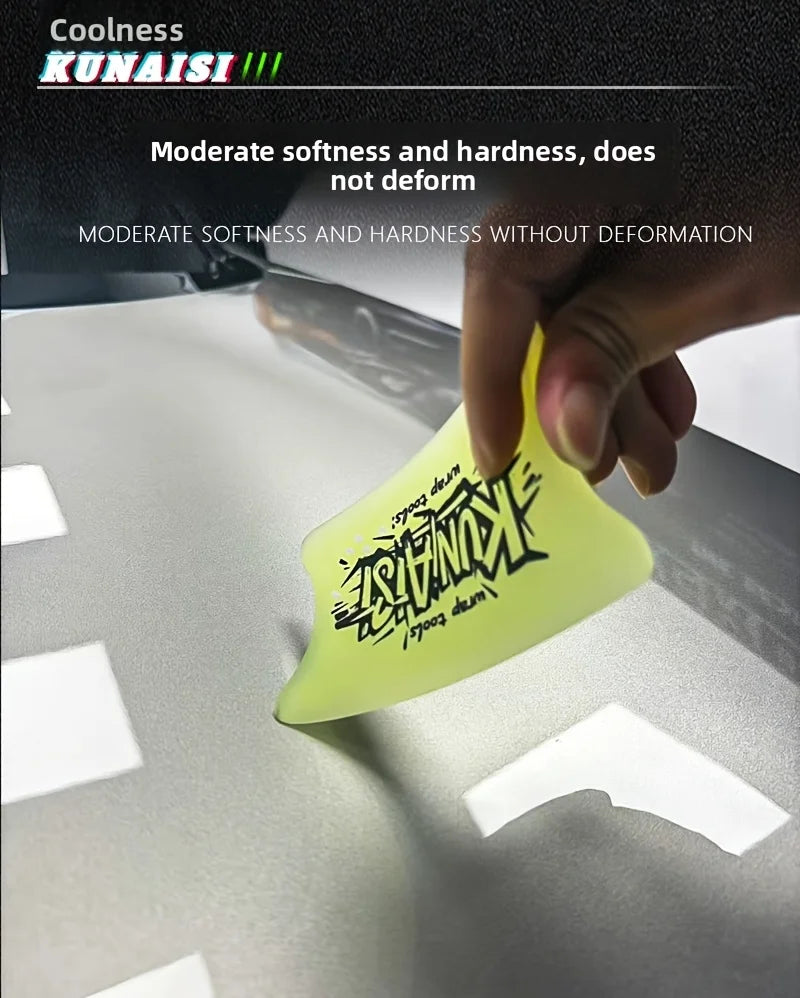 A hand is pressing a yellow TPU car wrap film squeegee onto a silver surface.