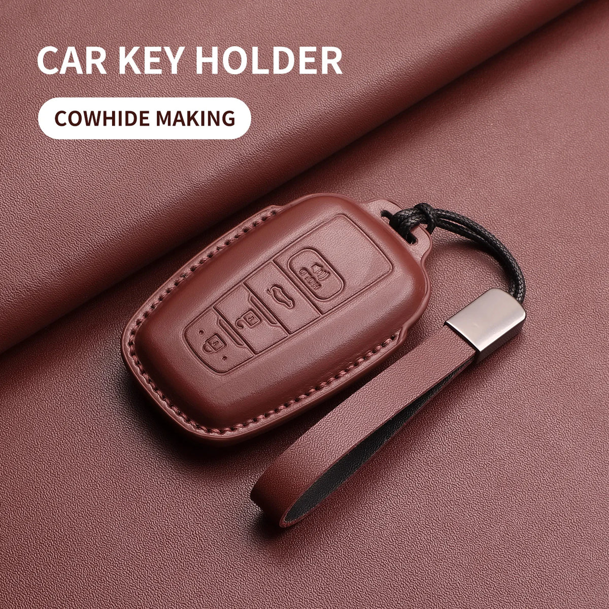 A brown genuine leather car key holder with a black strap is shown on a maroon surface.