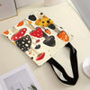 A canvas tote bag featuring a vibrant print of various mushrooms in orange, black, and red on a white background.