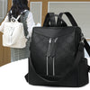 A black leather backpack with a floral pattern is shown against a light brown background.