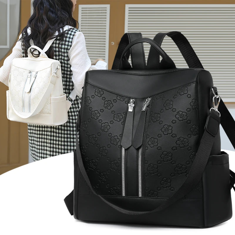 A black leather backpack with a floral pattern is shown against a light brown background.