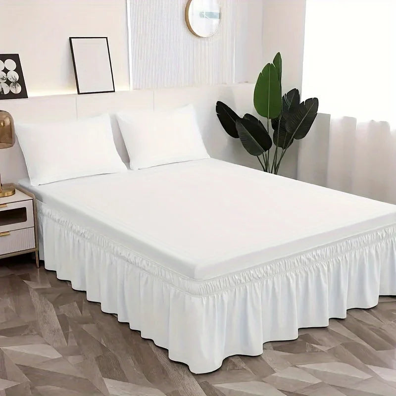 Un lit blanc avec une jupe élastique anti-poussière et des oreillers blancs dans une chambre moderne.
