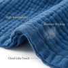 Close-up of a blue cotton muslin throw blanket showing features like high breathability, moisture wicking, and cloud-like tou