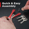 A hand is assembling an aluminum key clip with a carabiner hook and several keys on a dark surface.