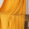 Flowing bright yellow fabric draped over a wooden surface.