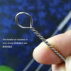 A hand holds a stainless steel reusable straw cleaning brush with a bendable handle against a blue background.