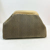 Primer plano de un bolso de mano tejido con patrón chevron negro y beige.