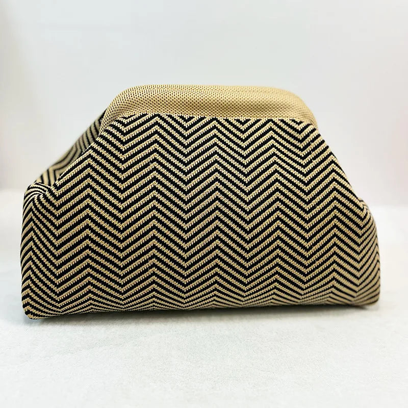 Primer plano de un bolso de mano tejido con patrón chevron negro y beige.