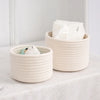 A natural beige handwoven cotton rope storage basket filled with white tissues and placed on a light surface.