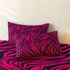 A set of three bold zebra print pillow covers in black and bright pink.