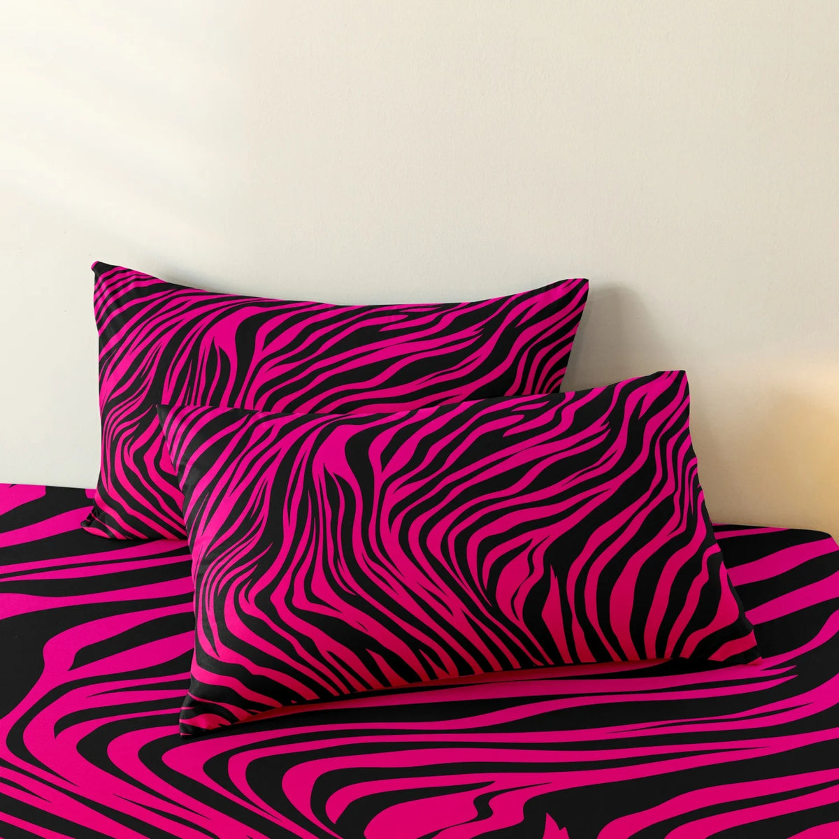 A set of three bold zebra print pillow covers in black and bright pink.