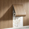A roll of wood grain peel-and-stick wall tiles is partially unrolled against a vertical wooden slat wall.