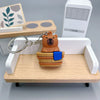 An adorable capybara keychain charm with a wooden body and blue accents displayed on a light wood tray.
