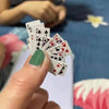 A hand holds a fan of playing cards showing various face cards and numbers for stress relief