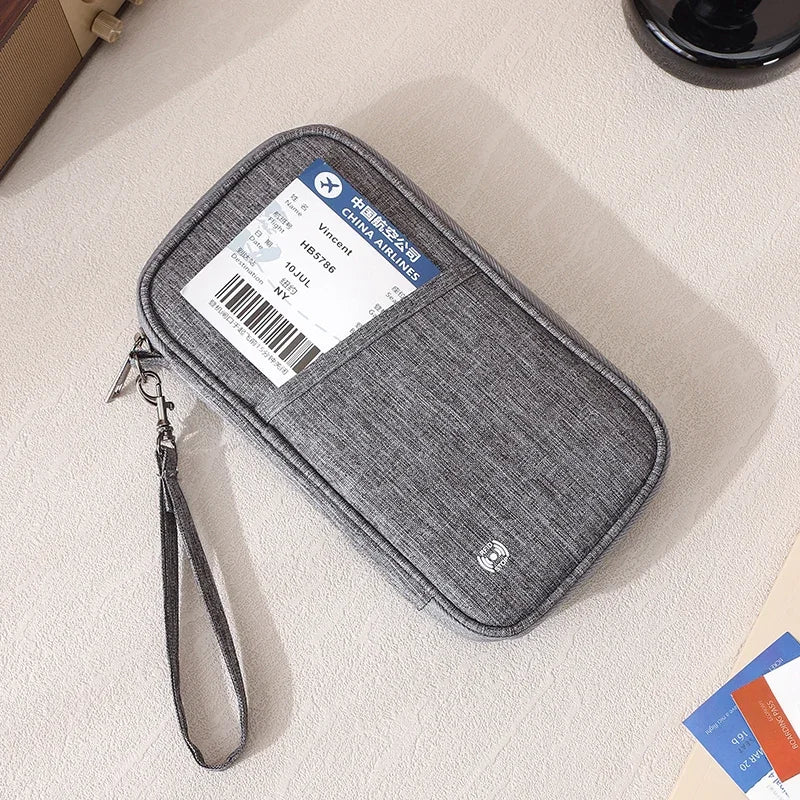 A gray RFID-blocking passport holder with a leather strap is shown on a light surface.