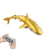 A golden shark toy is shown next to a hand holding a remote control.