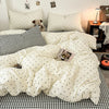 A white duvet cover set with black polka dots and a black and white checkered sheet is displayed on a bed.