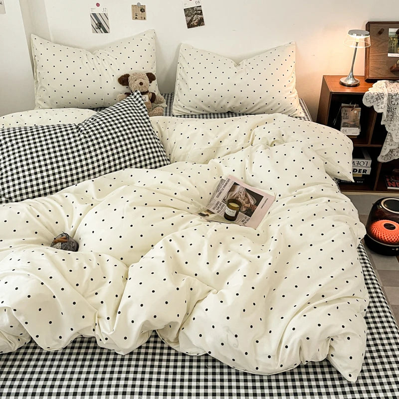 A white duvet cover set with black polka dots and a black and white checkered sheet is displayed on a bed.