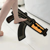 A novelty gun-shaped area rug is shown on a white floor next to a person's bare foot.
