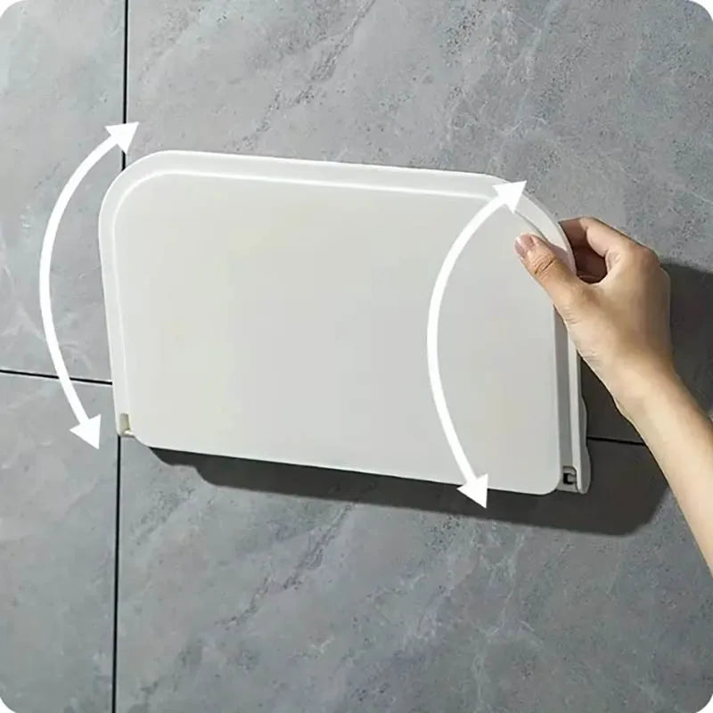 A hand is shown folding a white, rectangular wall shelf for space-saving storage.