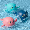 A set of wind-up bath toys featuring cartoon turtles, ducks, and whales floating in clear water.