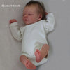 A newborn baby doll with painted veins and a soft cloth body, lying on a light surface.