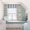 A bedroom featuring light blue wood grain wallpaper, a window with striped curtains, and a pale green bed frame.