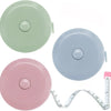 Three colored flexible soft tape measures, including green, light blue, and pink, with a coiled measuring tape visible.