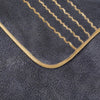 A dark gray towel with gold stripes and a curved edge, showing the soft texture of coral fleece.
