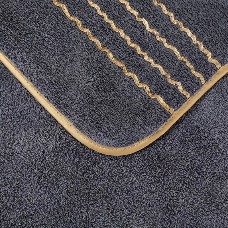 A dark gray towel with gold stripes and a curved edge, showing the soft texture of coral fleece.