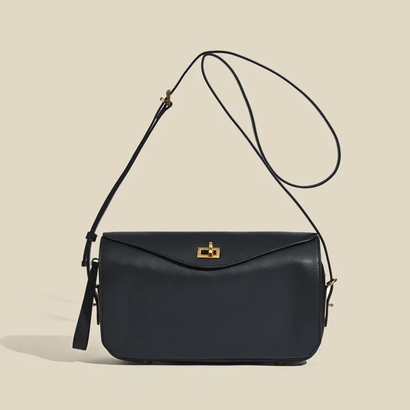 A dark navy genuine leather square crossbody bag with a gold lock and thin black strap.