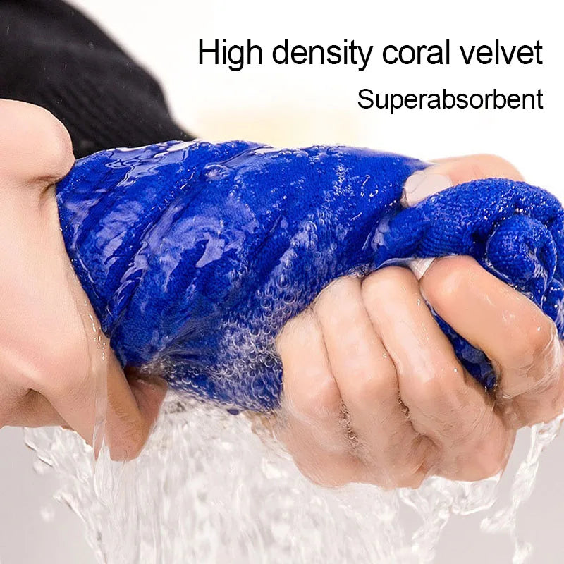 A hand is squeezing a bright blue, high-density coral velvet towel that is soaking in water.