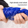 A hand is squeezing a bright blue, high-density coral velvet towel that is soaking in water.