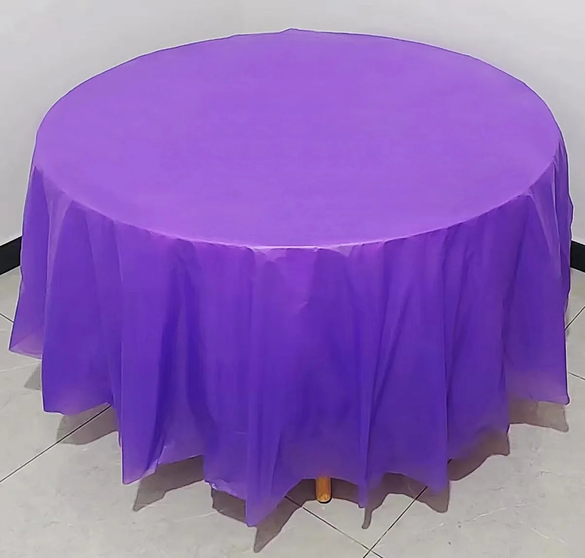 A vibrant purple disposable round tablecloth is spread on a table for parties or events.