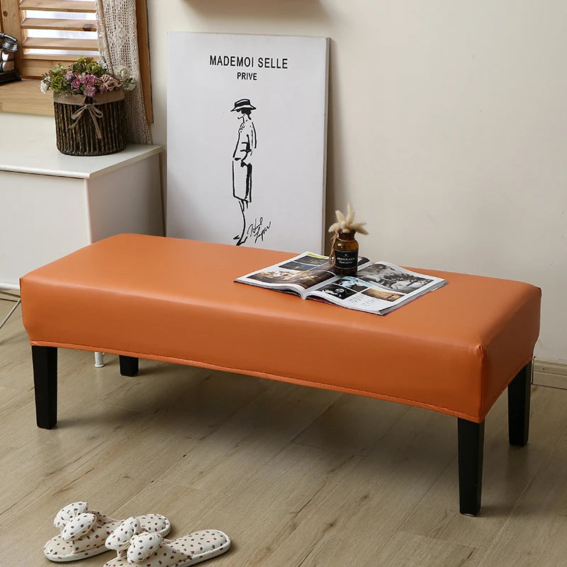 An orange waterproof PU stretch bench cover placed on a wooden floor in a room with a framed artwork.