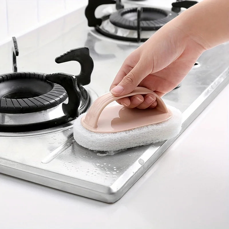 A hand is using a pink magic sponge scrubber with a long handle to clean a stovetop.