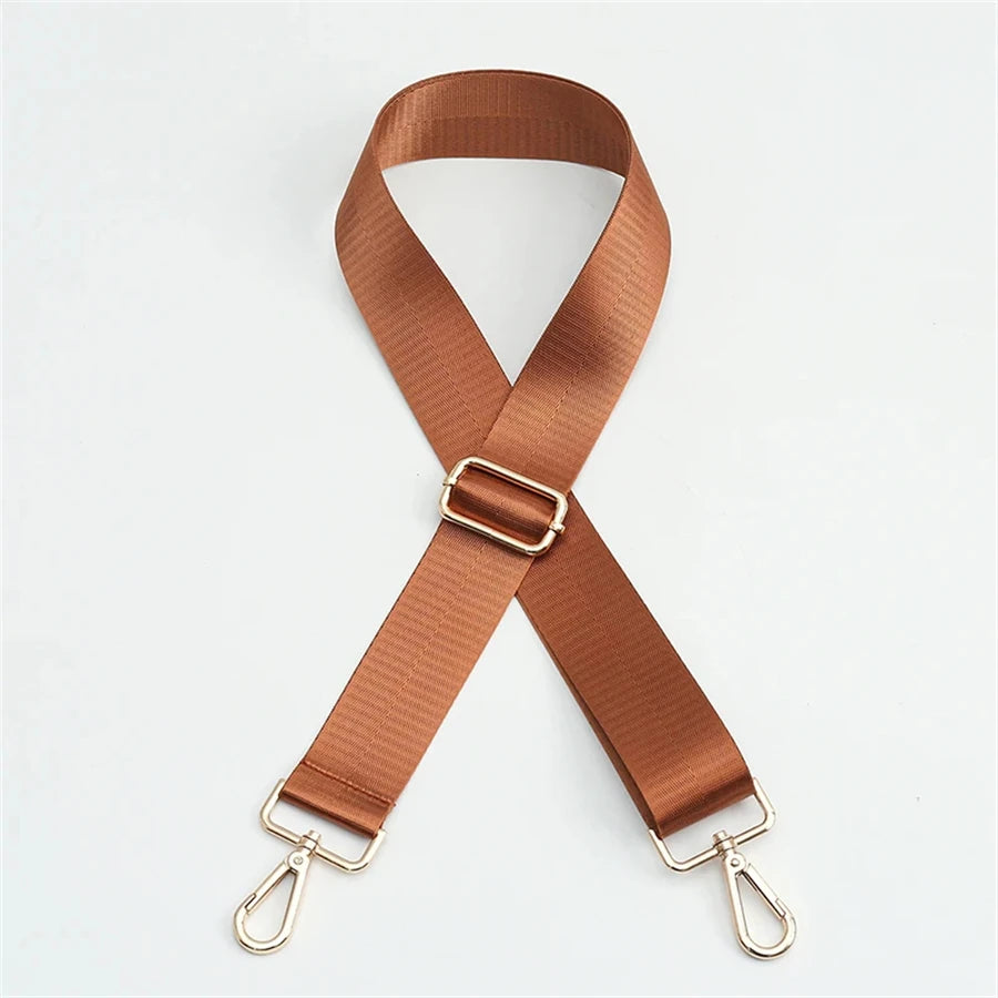 A brown nylon bag strap with a gold buckle shown in an 'X' shape.