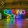 Neon sign spelling out GAMING ZONE in vibrant blue, pink, and green lights displayed on a wooden surface.