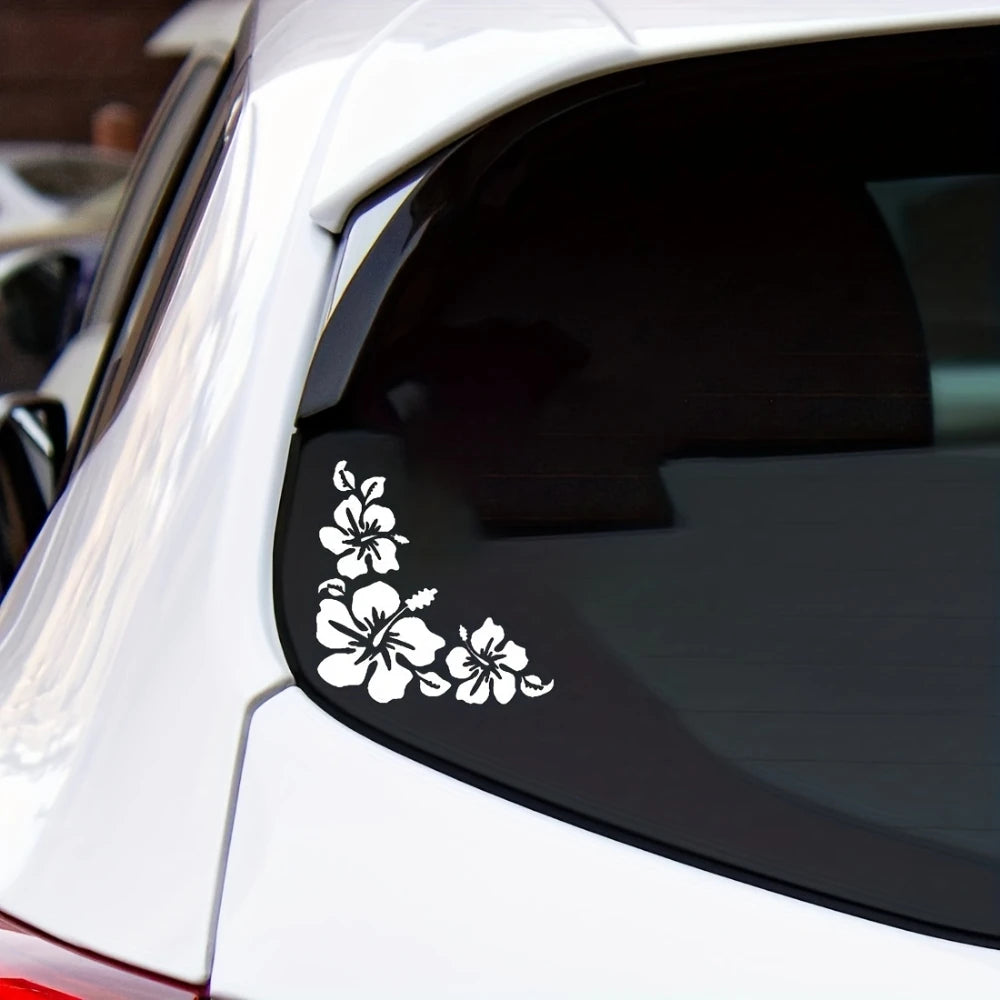 A close-up of a white car window featuring a white hibiscus flower decal sticker.